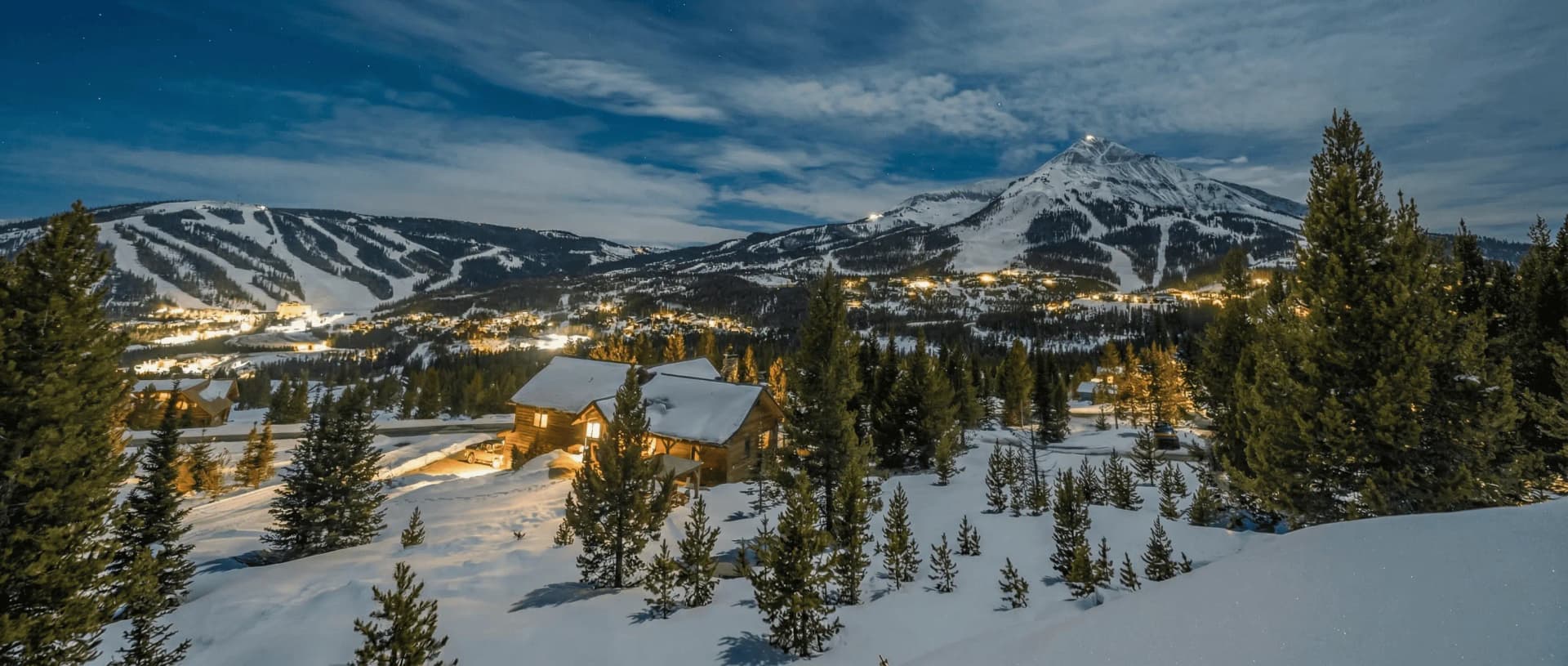 Big Sky Montana ski resort 2026 winter - aerial view of Lone Peak summit at 11,166 feet with fresh powder snow, 40 ski lifts accessing 320 runs across 5,850 acres, mountain village base area with luxury lodges and skiers on groomed trails under blue Montana sky