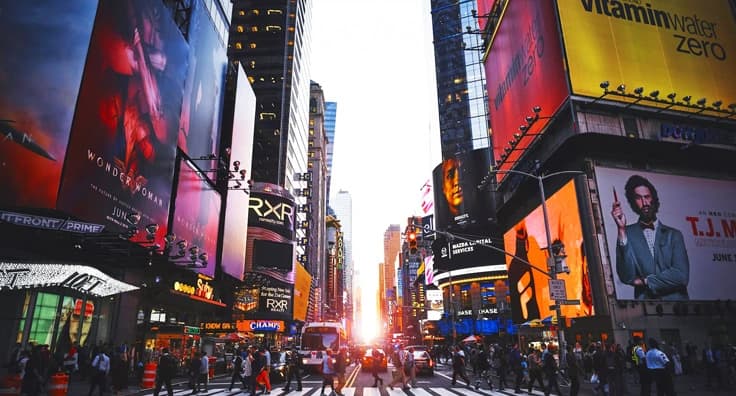 New York City Times Square at sunset with bright billboards, busy streets and iconic yellow taxi cabs - Grand Palace Hotel location