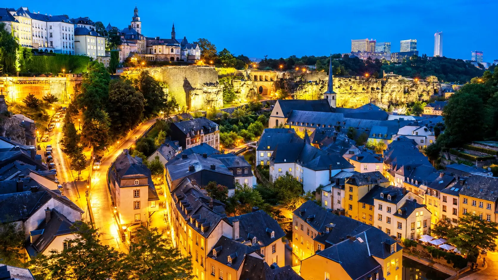 Picturesque Grund neighborhood in lower Luxembourg City with the tranquil Alzette River flowing past colorful historic houses, the ancient Neumünster Abbey cultural center, romantic waterside restaurants, and charming boutique guesthouses from €70 per night