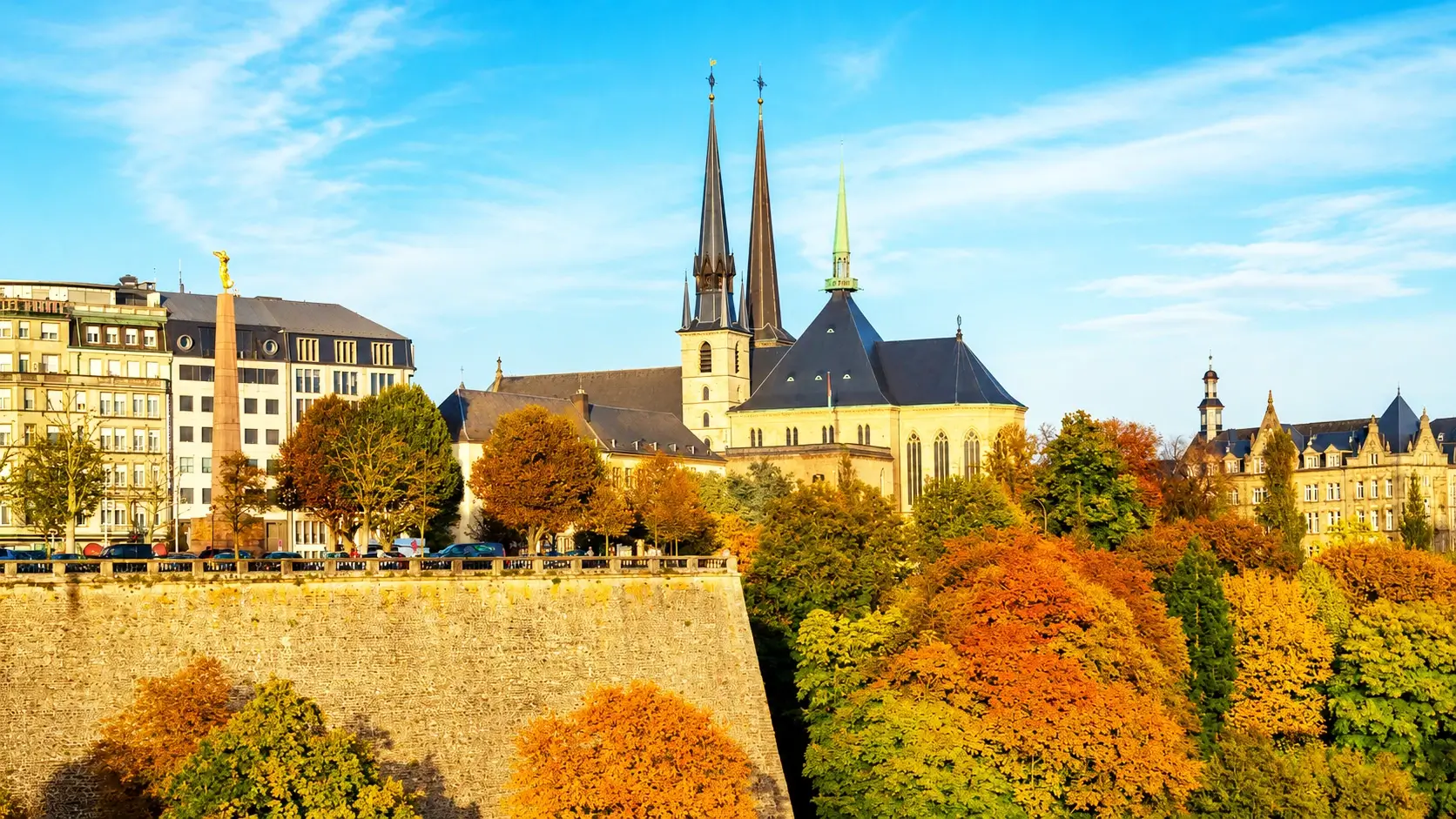 Ville Haute neighborhood in Luxembourg City showing cobblestone streets of the UNESCO-listed Old Town, the Grand Ducal Palace with guards, tree-lined Place d'Armes square with outdoor cafes, and historic boutique hotels where rooms start at €124 per night