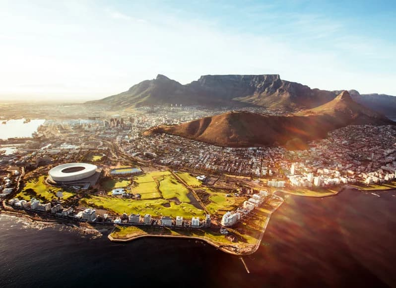 South Africa in November 2025 - iconic Table Mountain towering over Cape Town harbor with spring jacaranda blooms, golden beaches along Atlantic coastline, Kruger National Park baby elephants in green savanna during shoulder season wildlife viewing