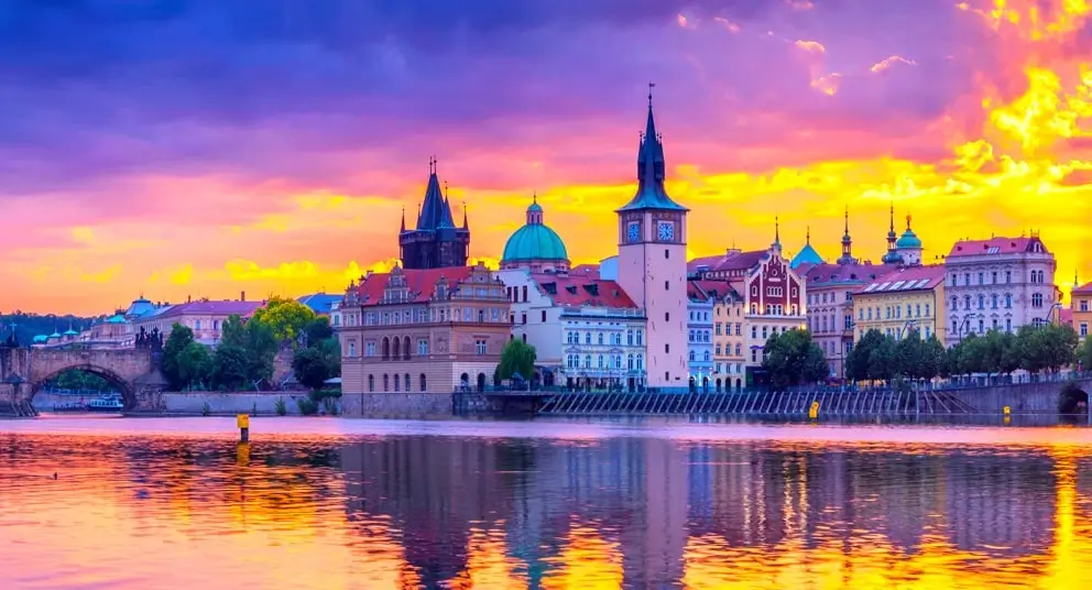 Prague Czech Republic 2026 travel guide - stunning aerial view of Charles Bridge at golden hour with Vltava River, Old Town Square Astronomical Clock, Gothic Týn Church spires, Prague Castle on Hradčany hill, red terracotta rooftops, UNESCO World Heritage Baroque architecture, 6 neighborhoods including Old Town Malá Strana Vinohrady Žižkov, budget-friendly European capital 40% cheaper than Paris