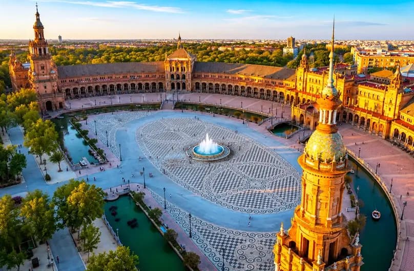 Seville Spain travel guide 2026: Plaza de España panoramic view with Renaissance architecture, ceramic tile alcoves, canal boats, Real Alcazar Mudéjar palace gardens, Seville Cathedral Giralda tower, Santa Cruz Jewish Quarter cobblestone streets, Triana flamenco neighborhood, tapas bars - 16+ verified hotels from €50/night