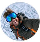 Jake Morrison - Austrian ski expert and winter sports journalist specializing in Alpine ski resorts, photographed outdoors wearing adventure gear with mountain scenery in background