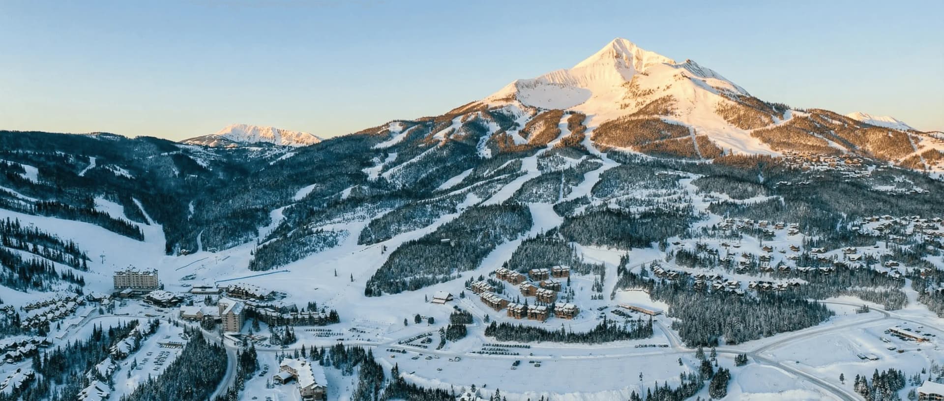Big Sky Resort Montana skiing 2026 - panoramic mountain vista showing Lone Peak Tram, ski lifts on Andesite Mountain, powder snow terrain with skiers, Madison Base Area gondola, and luxury ski-in ski-out lodges in Mountain Village base