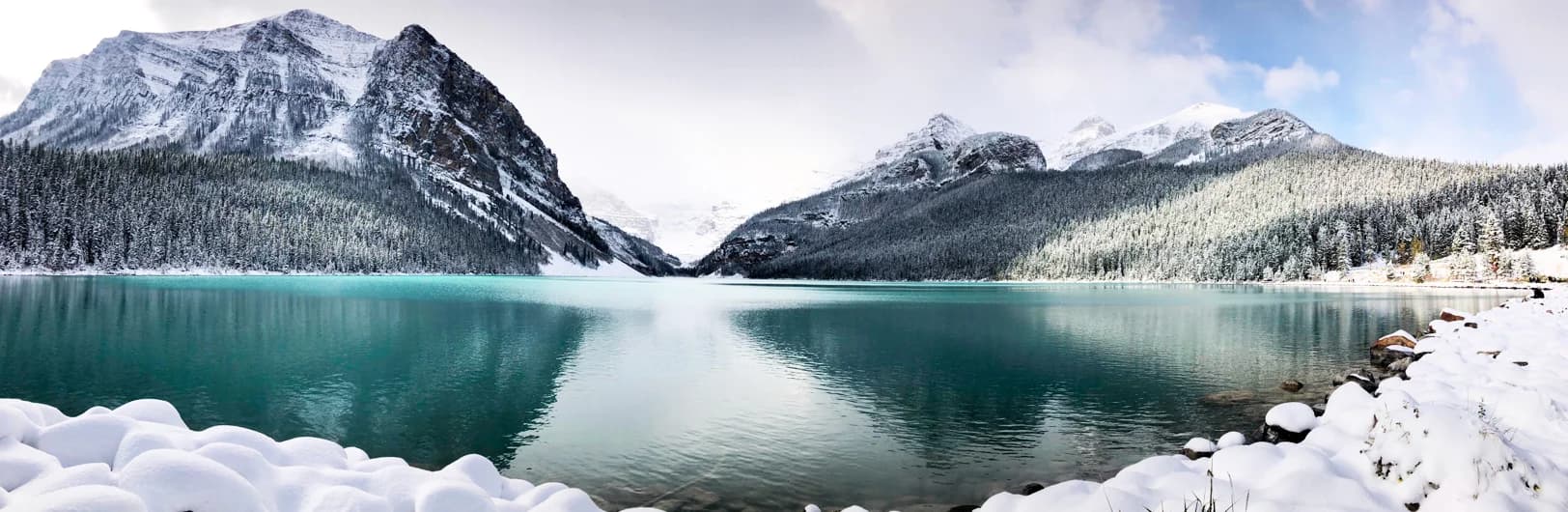 Lake Louise ski resort spectacular mountain view featuring iconic turquoise glacial lake reflecting Victoria Glacier, Fairmont Chateau Lake Louise historic hotel at lakefront, snow-covered Canadian Rockies peaks, ski runs descending four mountain faces, and Banff National Park pristine wilderness - Alberta's premier ski destination 4,200 acres 2026