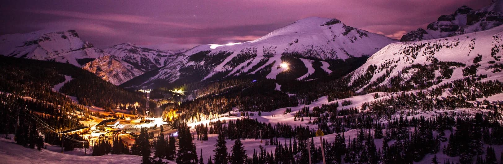 Sunshine Village ski resort dramatic alpine scenery at 2,730m summit elevation showing steep Delirium Dive extreme terrain with warning signs, Continental Divide mountain ridge straddling Alberta-BC border, deep champagne powder snow covering slopes, Sunshine Mountain Lodge ski-in ski-out accommodation, and skiers enjoying Canada's longest season extending to May - Banff's highest ski area 2026