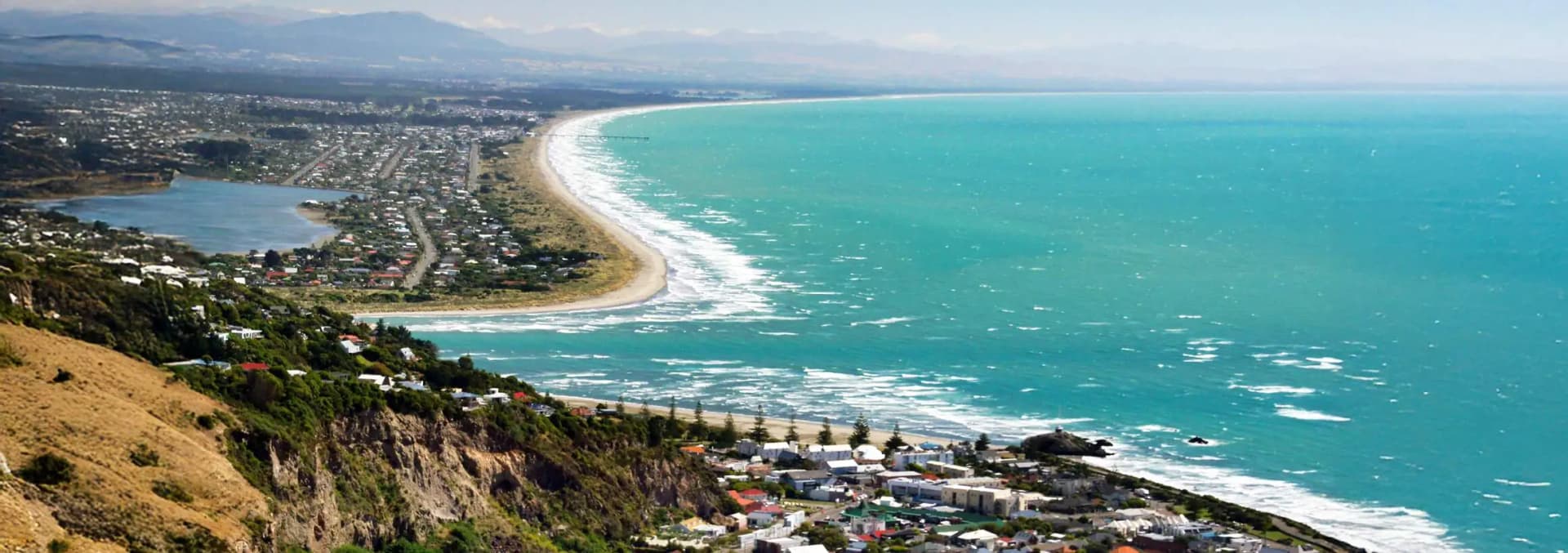 Sumner Beach Christchurch New Zealand - coastal seaside village with golden sand surf beach, beachfront cafes and restaurants along Naiper Street, Cave Rock landmark sea stack, coastal walking trails to Taylors Mistake and Godley Head, surfers catching waves, Scarborough cliffs, and vibrant summer beach culture in Canterbury