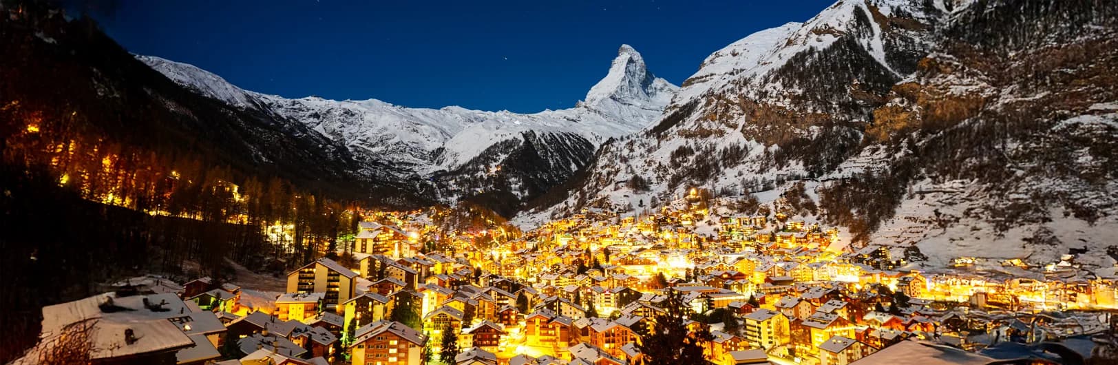 Zermatt car-free ski resort village Switzerland with iconic Matterhorn mountain peak backdrop - traditional wooden Swiss chalets, luxury alpine hotels, year-round glacier skiing terrain, electric taxis on village streets, and snow-covered slopes in Swiss Alps winter 2026